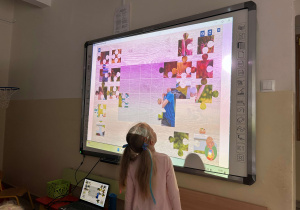 Dziewczynka układa puzzle na tablicy interaktywnej