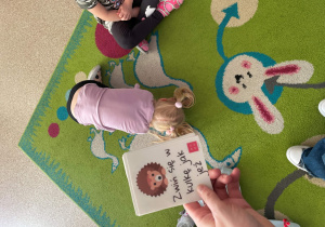 Dziewczynka naśladuje zwiniętego w kulkę jeża