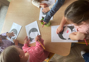 Dzieci siedzą i wykonują karty pracy związane z Dniem Uśmiechu
