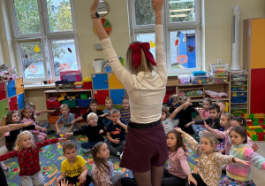 Nauczycielka prezentuje dzieciom zabawę ruchową