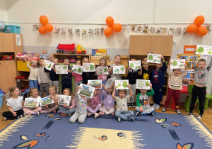 Dzieci pozują do zdjęcia z planszami edukacyjnymi z okazji Dnia Drzewa