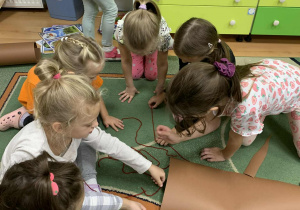 Dzieci siedzą na dywanie i wykonują korzenie drzewa