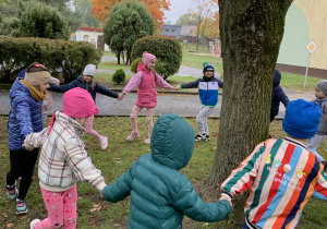 Dzieci bawią się dookoła drzewa
