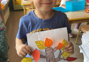 Chłopiec pozuje do zdjęcia z wykonaną pracą