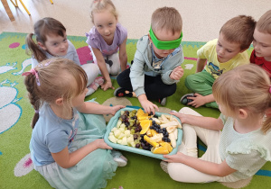 Chłopiec z zasłoniętymi oczami próbuje owoców