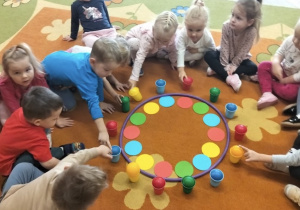 Dzieci uczestniczą w zabawie na dywanie o kolorach