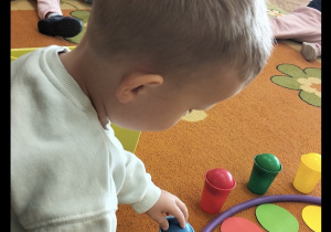 Chłopiec uczestniczy w zabawie na dywanie