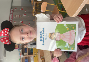 Dziewczynka trzyma plakat z okazji Dnia Postaci z Bajek