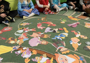 Dzieci oglądają postacie z bajek rozsypane na dywanie
