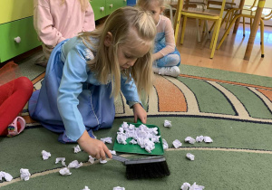 Dziewczynka zbiera gazety na szufelkę