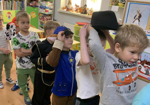 Dzieci podają sobie kapelusz z głowy na głowę