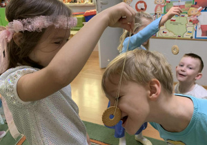 Chłopiec próbuje zjeść ciastko zawieszone na sznureczku