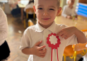 Chłopiec pozuje do zdjęcia z kotylionem