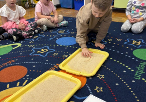 Dzieci piszą litery l na piasku