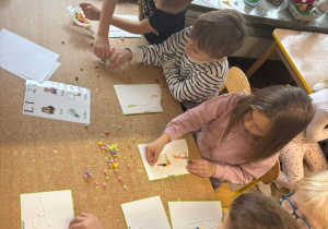 Dzieci układają literę L z materiałów kreatywnych