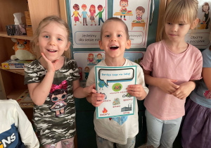 Dzieci pozują do zdjęcia z planszą tematyczną