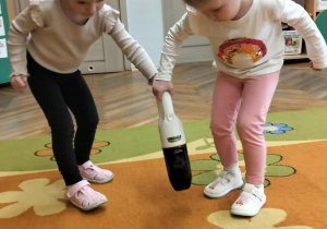 Dziewczynki odkurzają dywan