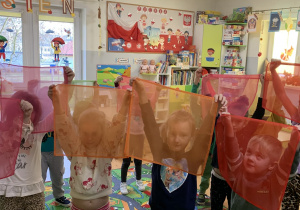 Dzieci podnoszą do góry chustki