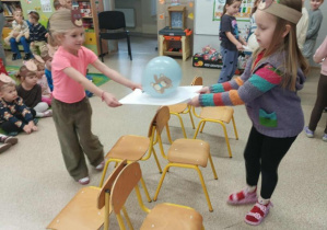 Dwie dziewczynki przenoszą balon na kartonie