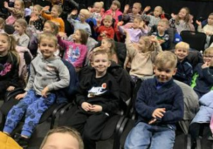 Dzieci siedzą w sali teatralnej