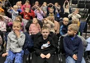 Dzieci siedzą w sali teatralnej