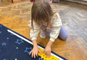 Dziewczynka układa z klocków 1 m długości