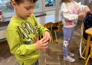 Dzieci ćwiczą motorykę małą zwijając miarkę