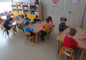 Dzieci pracują przy stolikach podczas pracy plastycznej