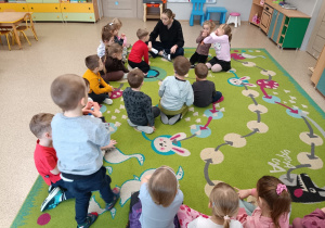Dzieci siedzą na dywanie i słuchają listu