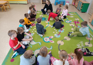 Dzieci siedzą na dywanie i słuchają listu