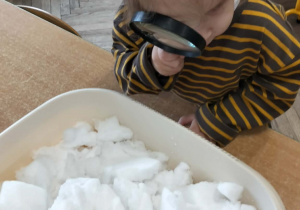 Dziewczynka ogląda lupą śnieg