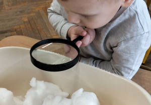 Chłopiec ogląda lupą śnieg