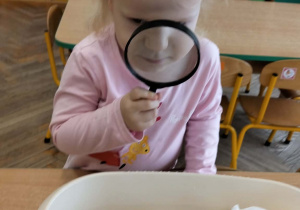 Dziewczynka ogląda lupą śnieg