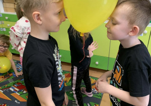 Chłopcy trzymają balon głowami