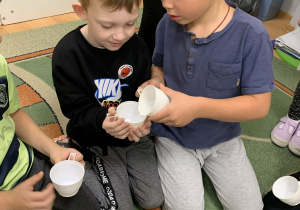 Chłopcy przelewają wodę z kubka do kubka