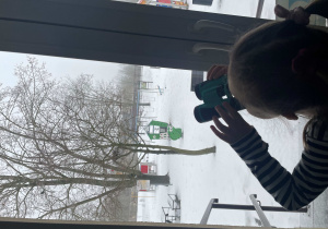 Dziewczynka wypatruje ptaków przez lornetkę