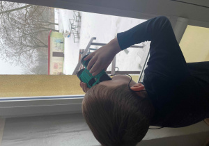 Chłopiec wypatruje ptaków przez lornetkę