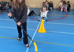 Dziewczynka bierze udział w zawodach sportowych tocząc piłkę