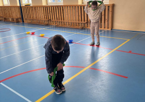 Dzieci biorą udział w zawodach sportowych i przekładają przez siebie szarfę