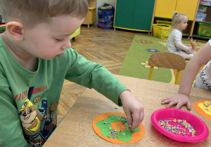 Chłopiec posypuje pączka