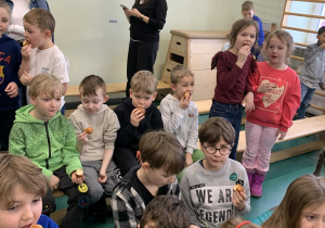 Dzieci jedzą pączki rozdane przez uczniów