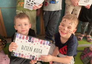 Dzieci pozują do wspólnego zdjęcia z okazji Dnia Kota