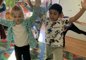 Dzieci wykonują ćwiczenia ruchowe- stoją na jednej nodze