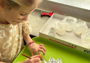 Dziewczynka przygotowuje śnieżynkę do pracy plastycznej