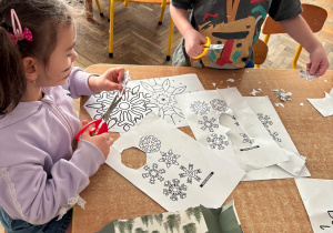 Dzieci samodzielnie wycinają śnieżynki do pracy plastycznej