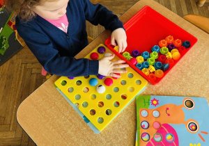 Dziewczynka układa pionki na planszy