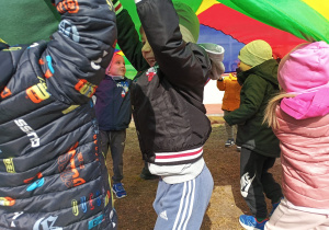 Zabawa ruchowa z tęczową chustą animacyjną na świeżym powietrzu.