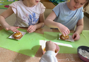 Dziewczynki ozdabiają ciastka jadalnymi kwiatkami