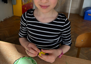 Dziewczynka lepi kurczaczka z plasteliny