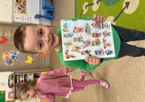 Chłpiec trzyma plansze edukacyjną